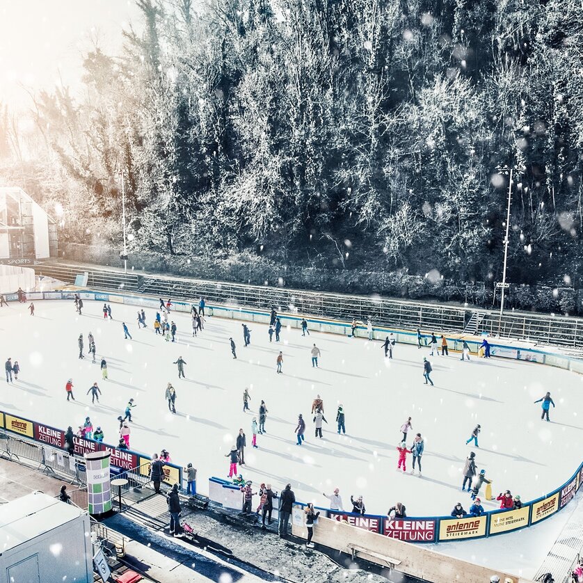 Advent in Graz I Graz Winter World I Ice skating rink | © Simon Möstl People skate on a lit ice rink in Graz, surrounded by a winter landscape. | © Simon Möstl