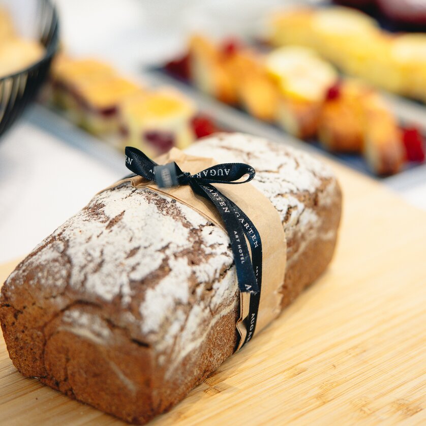 Una pagnotta di pane marrone decorata con un fiocco e il logo dell'Augarten Art Hotel | © Augartenhotel x einsnullneun