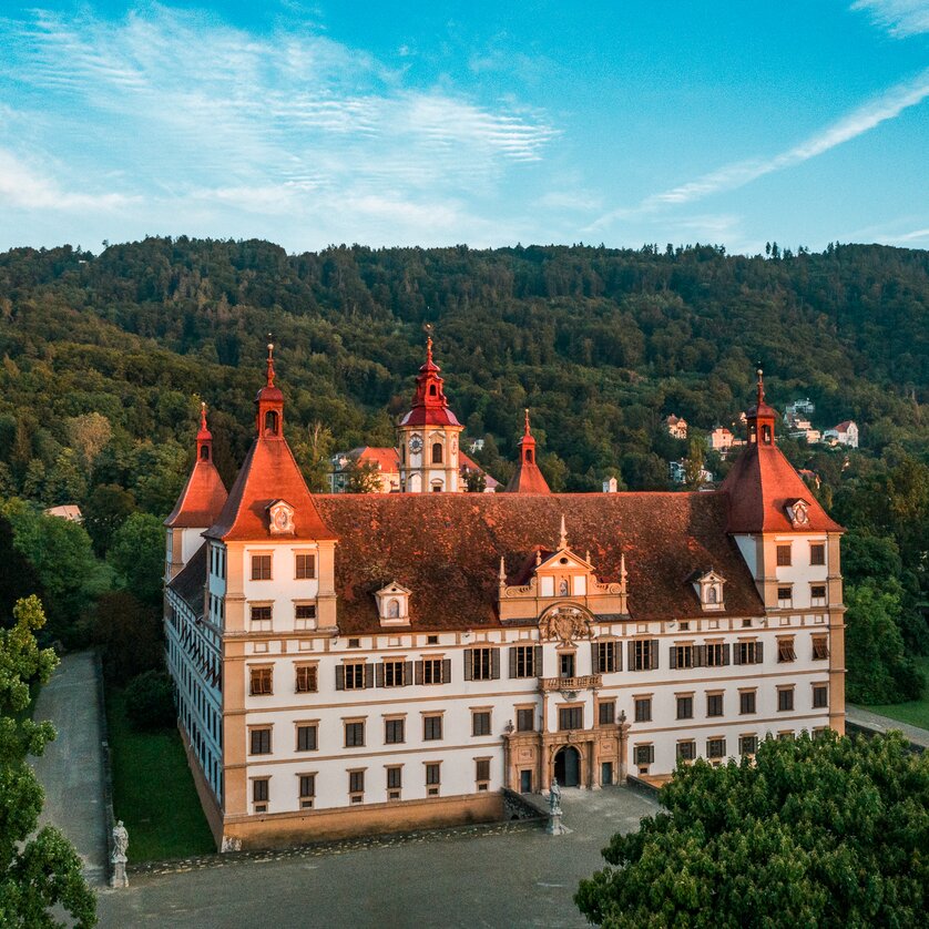Eggenberg Palace in Graz | © Graz Tourismus - Mias Photoart A view of Eggenberg Palace, surrounded by trees and mountains. | © Graz Tourismus - Mias Photoart