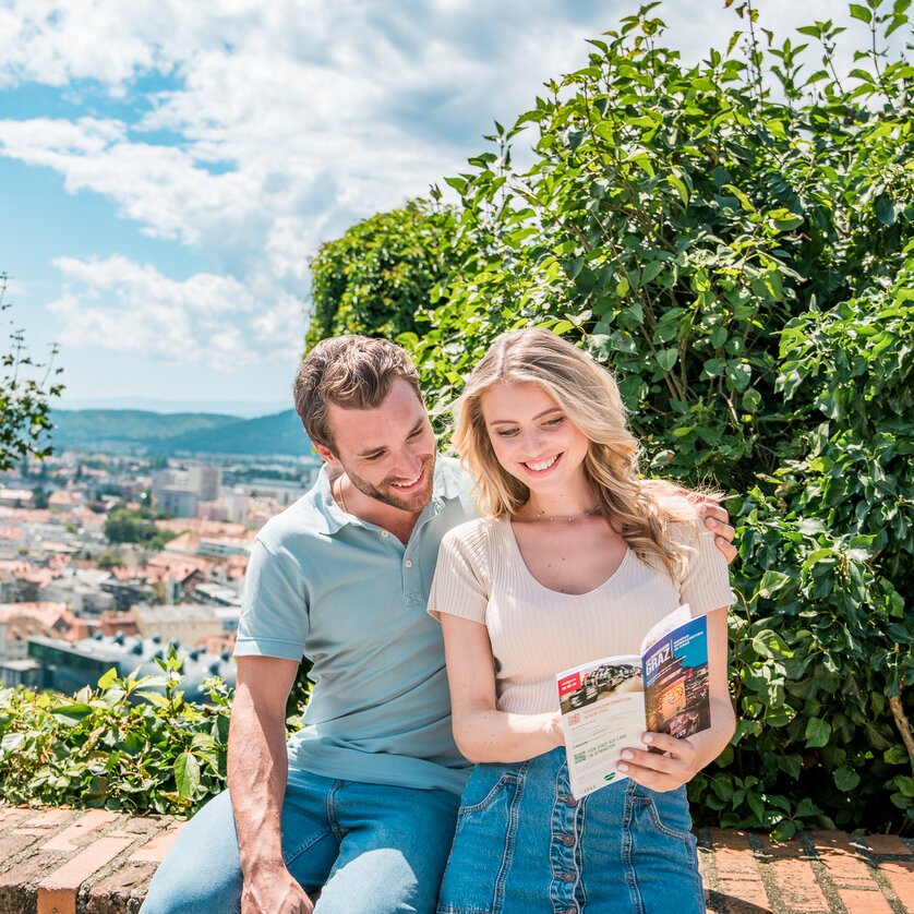 View from the Schlossberg in Graz | © Graz Tourismus - Mias Photoart Couple looks at a city map with a view of Graz. | © Graz Tourismus - Mias Photoart
