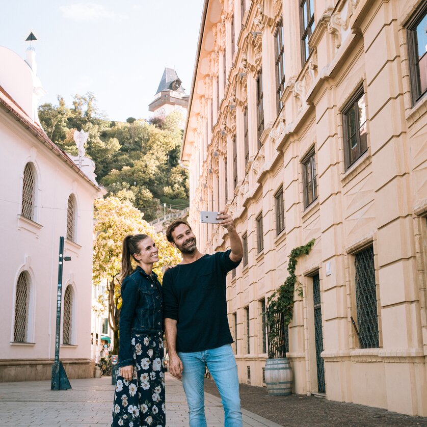 Schlossbergplatz mit Blick auf den Grazer Uhrturm | © Graz Tourismus Ein Paar macht ein Selfie in der Stadt Graz, mit dem Grazer Uhrturm im Hintergrund. | © Graz Tourismus